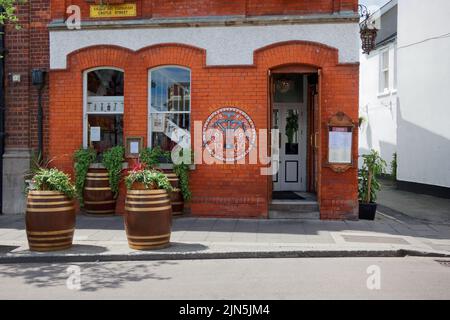 The 1909 Restaurant and Wine Bar in Dalkey town. Restored building with logo painted on the wall and decorative potted flowers on barrels at the front Stock Photo