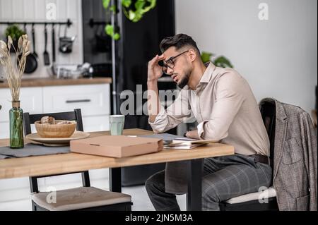 Sad man touching head sitting at table Stock Photo