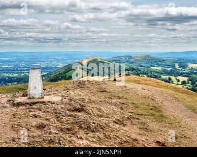Trig point at the summit of Worcestershire Beacon looking south to Herefordshire Beacon in the Malvern Hills AONB England Stock Photo