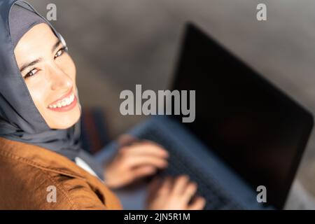 Top view of a smiling muslim woman working with laptop Stock Photo