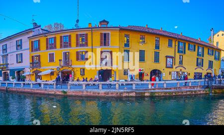MILAN, ITALY - APRIL 9, 2022: Panorama of Naviglio Grande Canal, its pedestrian embankment, old houses, cafes and bars, on April 9 in Milan Stock Photo