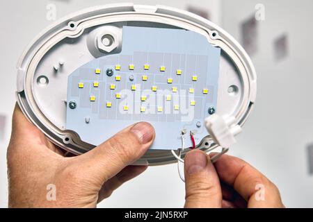 Installing LED wall light fixture, electrician connect connecting wires ...