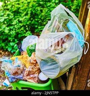 Berlin, Germany - June 10, 2022: Overfilled dustbin and waste in a public park in Berlin. Stock Photo