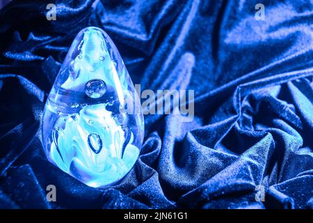 Closeup shot of a Blue-Violet Egg shaped glass ball on the Blue-Violet velvet cloth Stock Photo