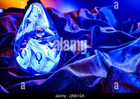 Closeup shot of a Blue-Violet Egg shaped glass ball on the Blue-Violet velvet cloth Stock Photo