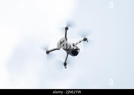 Kharkiv, Ukraine - April 22, 2021: Dji Mavic Mini 2 drone flying, bottom view. New quadcopter device hovering on gray sky background Stock Photo