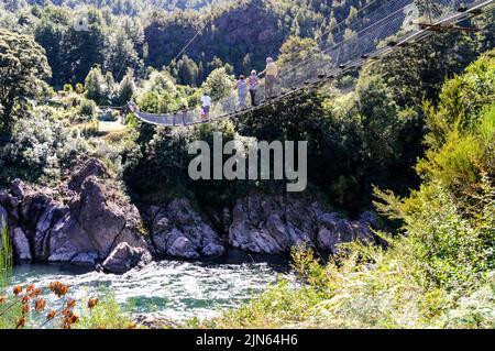 Two-way traffic as visitors cross New Zealand's longest swing bridge high above the Buller river at Buller Gorge Adventure & Heritage Park near Murchi Stock Photo
