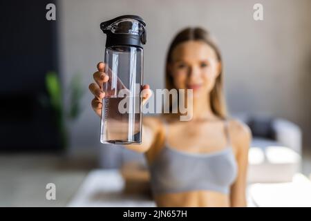 Keep hydrated. Young woman drinking water on yoga mat at home Stock Photo