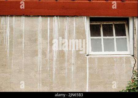 A closeup of an old concrete house with a red roof and white paint drips on the walls Stock Photo