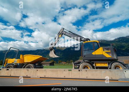 Yellow medium wheeled excavator with mini dumper Stock Photo