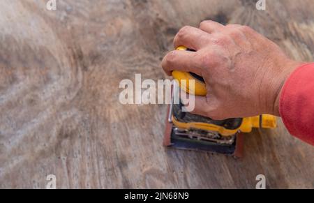 man's hand with electric sander on a wooden background doing work Stock Photo