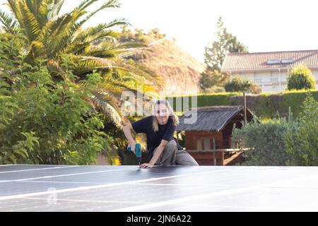 Young technician woman engineer working on a photovoltaic panels installation with a screwer Stock Photo