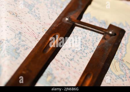 Vintage wooden parallel ruler lays on a nautical paper chart. It is a drafting instrument used by navigators to draw parallel lines on charts Stock Photo