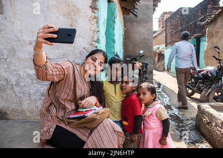 A social  worker is taking a selfie with young girls collecting garbage on the streets, as part of a clean up initiative taken up by their school. Stock Photo