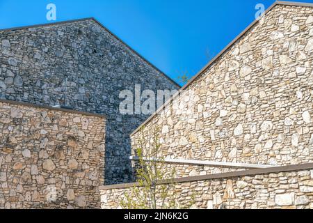 Buildings with stone wall cladding against the blue sky in Austin, Texas. Exterior of two buildings with walls at the front with uneven stone veneer w Stock Photo