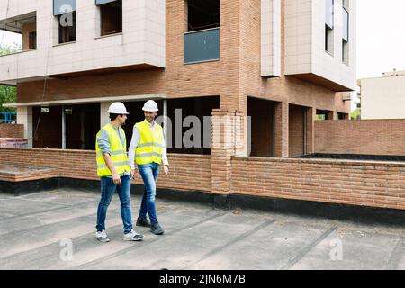 Professional engineers architect workers talking at building construction site Stock Photo