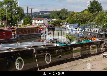 Small sailing boats and barges moored up at the side of the Leeds Liverpool canal at the top of Five Rise Locks in Bingley, West Yorkshire. Stock Photo