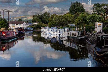 Barges and small sailing boats moored up at the side of the Leeds Liverpool Canal at the top of Five Rise Locks in Bingley, West Yorkshire. Stock Photo