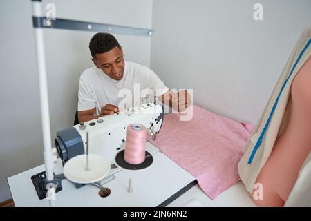 Male tailor using sewing machine at work Stock Photo