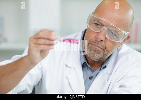 man with glasses looks at the flasks in his hand Stock Photo