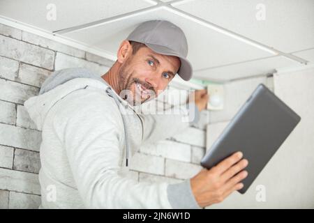 electrician with tablet computer installing alarm system indoors Stock Photo