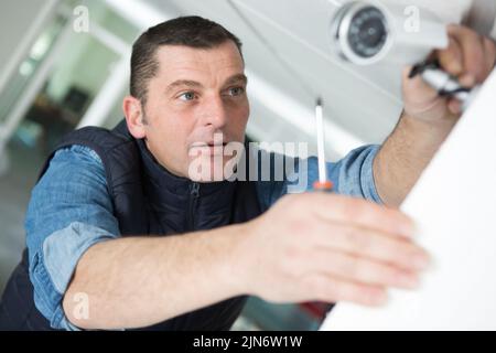 contractor installing surveillance cctv cameras in office Stock Photo