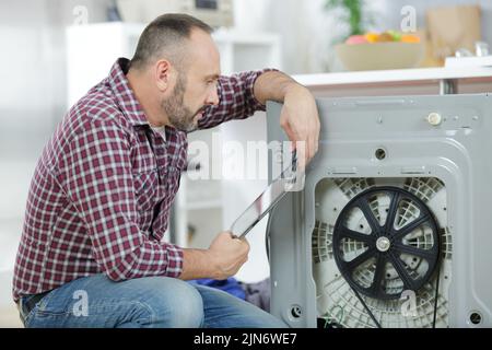 serviceman repairing washing machine looking at tablet Stock Photo