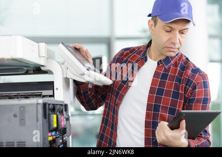 technician using a tablet to fix a printer Stock Photo