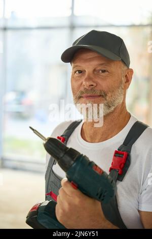 Portrait of bearded builder with drill in his hands Stock Photo