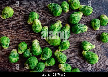 Fresh Brussels Sprouts Scattered on a Dark Wood Table: Overhead view of Brussels sprouts on a rustic wooden background Stock Photo