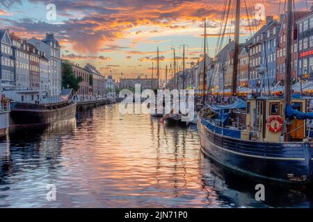 A beautiful shot of a famous tourist spot Nyhavn in Copenhagen with a waterscape and ducked boats Stock Photo