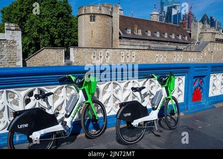 Lime electric hire bike scheme bicycles left outside the Tower of London on Tower Bridge Road. Dockless hire bicycles left on pavement in tourist area Stock Photo