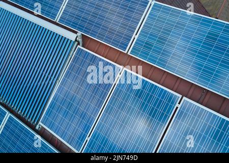 Photovoltaic panels and vacuum air solar collectors for water heating and producing of clean electricity mounted on house rooftop. Production of Stock Photo