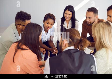 Multiracial men and women at support group meeting listen to young woman tell her story. Stock Photo