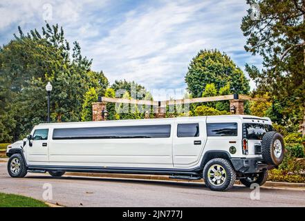White stretch Limousine SUV parked on street in leafy area Stock Photo