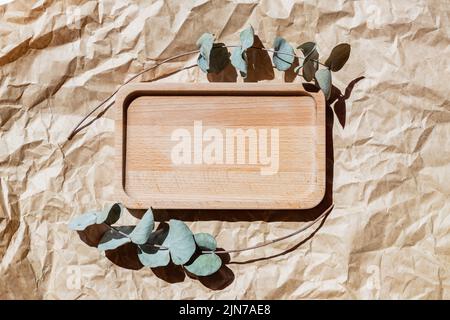 Wooden tray on pastel beige paper craft background. Card mockup. Elegant floral wedding layout. Eucalyptus branches. Minimal eco template. Aesthetic i Stock Photo