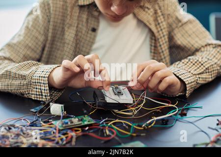 Close up of boy building robot and wiring circuit board during engineering class at school Stock Photo