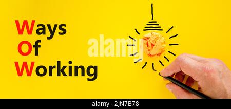 WOW ways of working symbol. Concept words WOW ways of working on a beautiful yellow background. Orange light bulb icon. Businessman hand. Business and Stock Photo