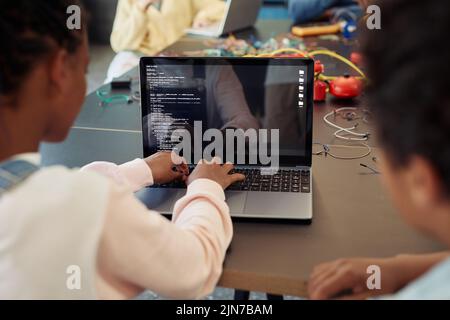 Back view of kids using laptop in engineering class and programming robots, copy space Stock Photo