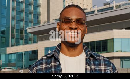 Portrait of man in city african american guy young student man in stylish sunglasses wears plaid shirt lookshappy friendly male face head looking at Stock Photo