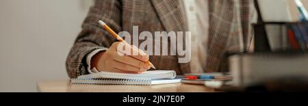 Close-up of unrecognizable business woman taking notes in notebook Stock Photo