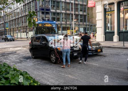 A woman holds up traffic while she gets a jump from a livery driver in Soho in New York on Saturday, July 30, 2022.  (© Richard B. Levine) Stock Photo