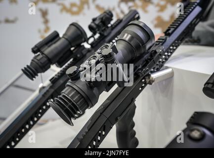 Black shooting scope optics mounted on metal bar displayed at weapons exhibition fair, closeup detail to adjustment knobs Stock Photo