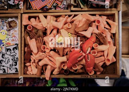 Old plastic doll parts in box at NYC Flea Market. Different sizes. Plus Lobster Claws Stock Photo