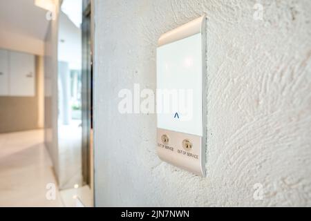 1st floor Elevator glass board stick on the white cement wall near the walkway. Stock Photo