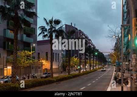 Barcelona, Spain - April 19 2022: View of street in one of the neighborhoods in Barcelona with apartment buildings on the side and palm trees dividing Stock Photo