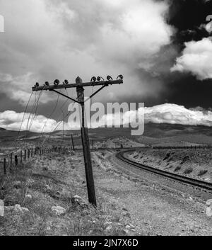 A vertical shot of a broken power line near a railroad on a cloudy day Stock Photo