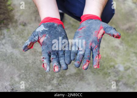 Defocus worn dirty and leaky gloves. Open palms of hands in worn workers gloves, protection against damage during operation, closeup on nature backgro Stock Photo