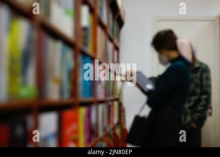 Defocus reading concept. Vintage tone of woman selecting book from a bookshelf. Portrait of girl in library reading book Female hand holding a book in Stock Photo