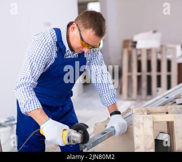 Focused man renovating home, cutting metal profile Stock Photo